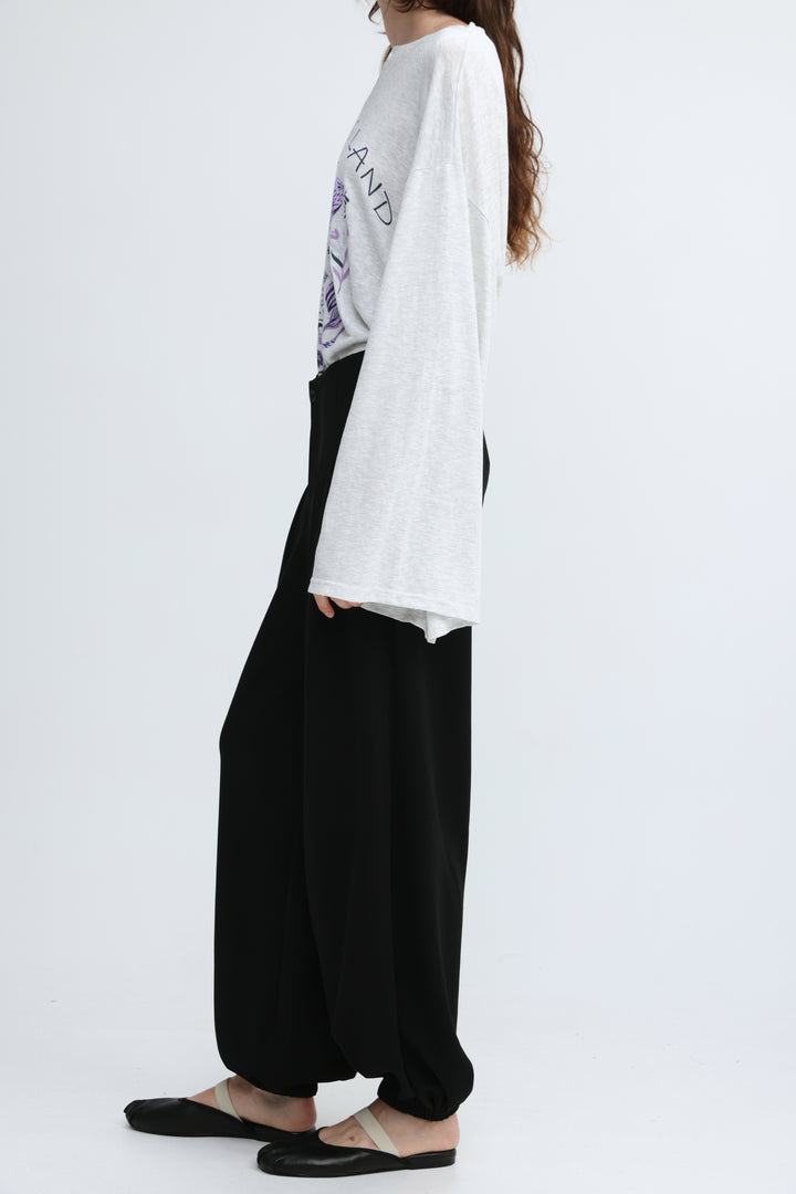 White oversized long-sleeve t-shirt with graphic print and loose fit shown from the front with everything black bottoms