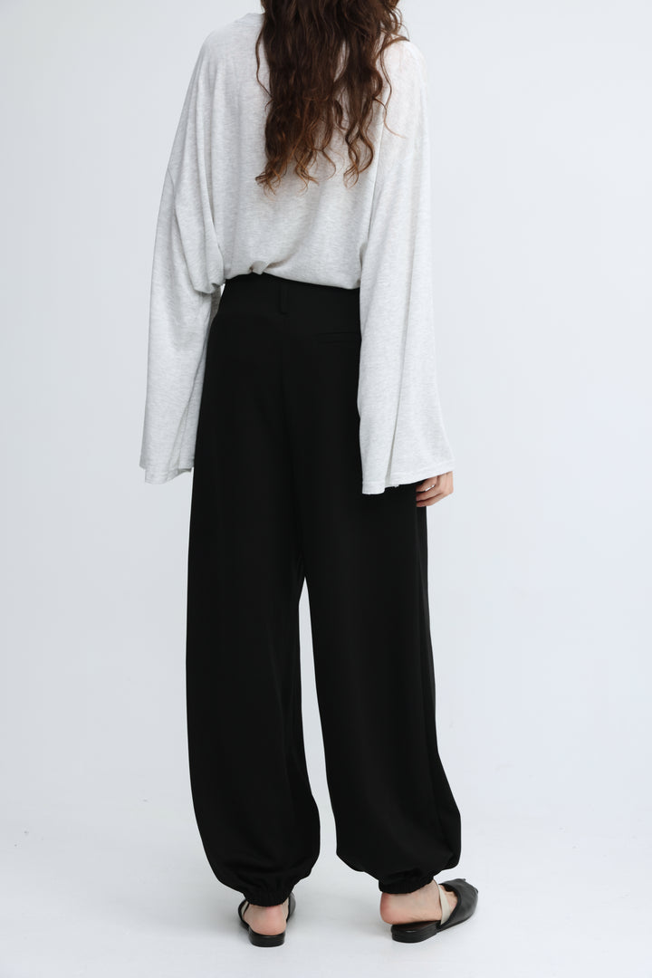 Black wide-leg harem pants with elastic cuffs shown from the front in everything black bottoms collection