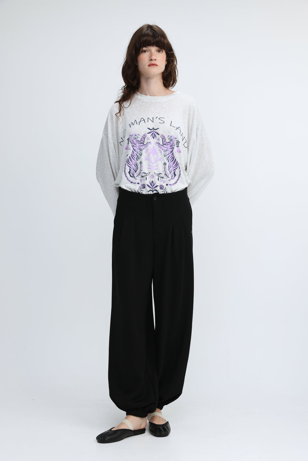 White long-sleeved sweatshirt with purple tiger graphic and no mans land text on chest paired with black bottoms front view