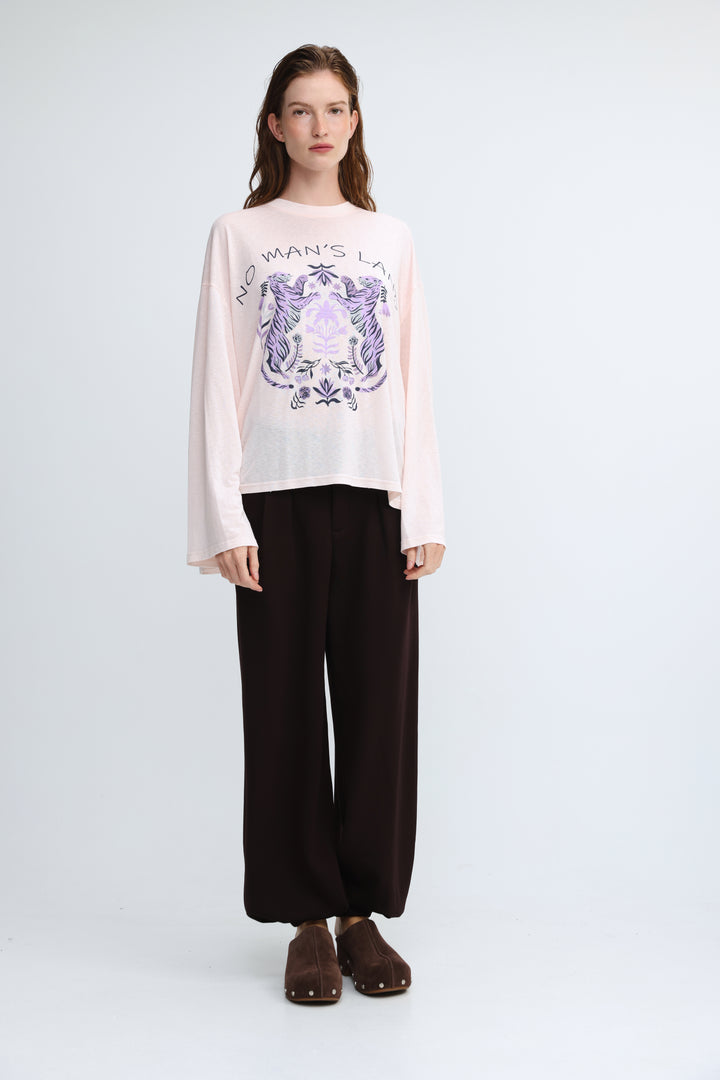 A soft pink long-sleeved top with a purple and white crest graphic and no mans land text on the chest front view