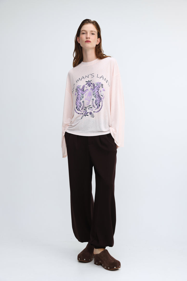 A soft pink long-sleeved graphic tee with a purple and black embroidered design and no mans land text on front