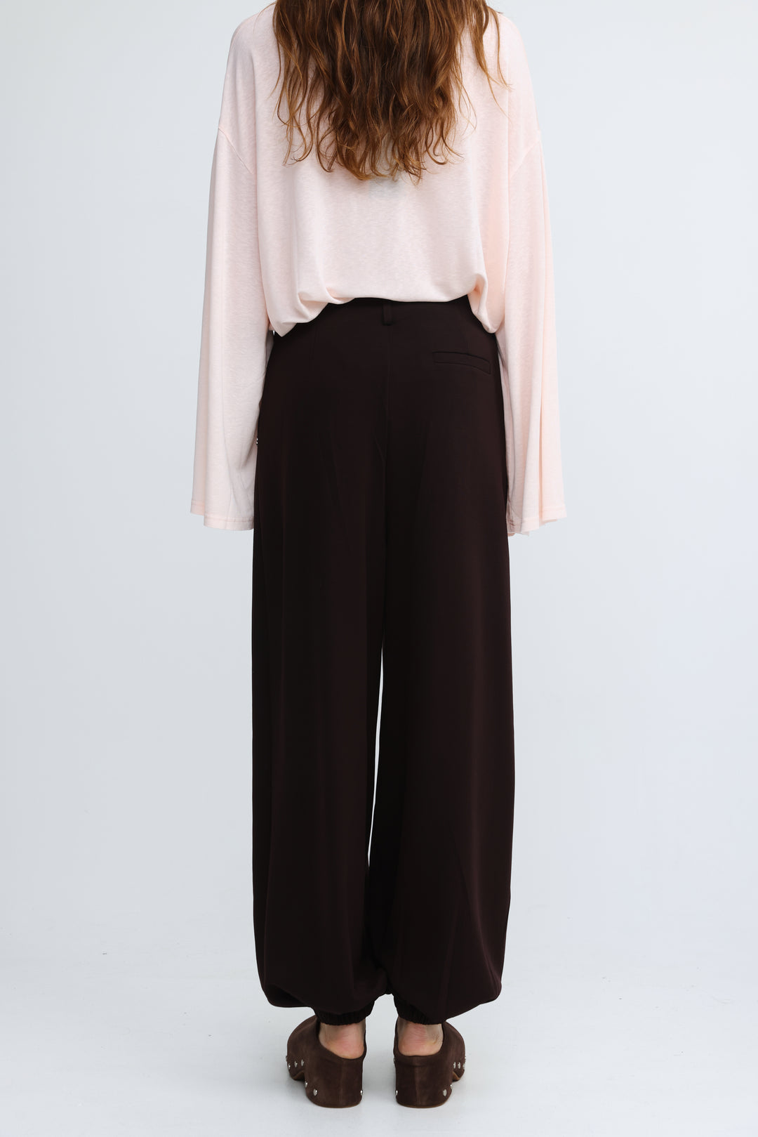 Black wide leg trousers from Everything Brown Bottoms with subtle waistband pleats and smooth flowing fabric front view