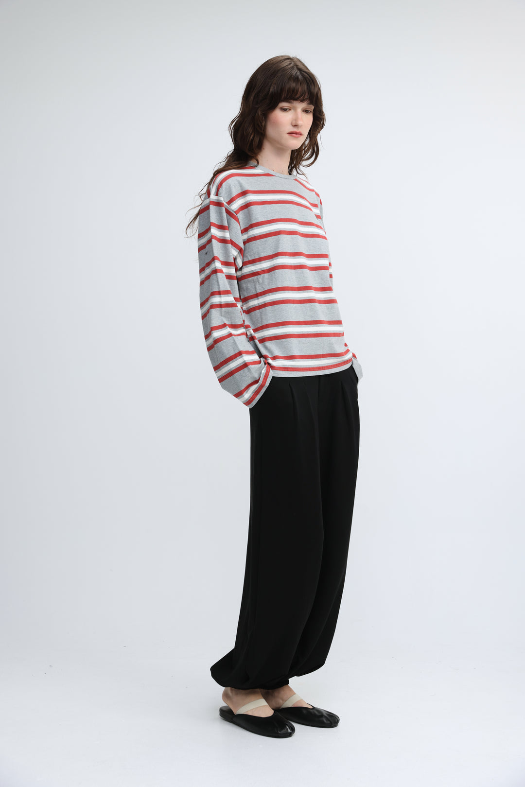A woman wearing a federer grey striped long-sleeved shirt with horizontal soft gray and coral red stripes visible from front