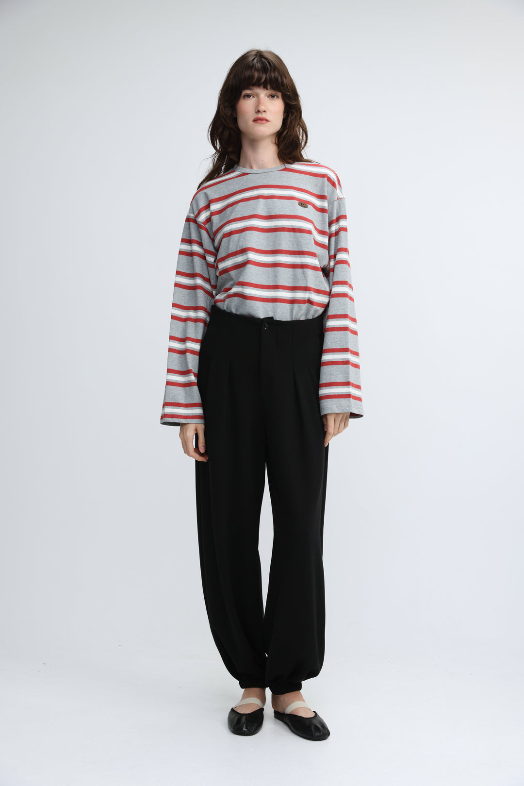 A woman wearing a front view of a federer grey striped long-sleeved shirt with black pleated pants