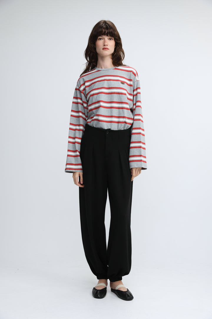 A woman wearing a front view of a federer grey striped long-sleeved shirt with black pleated pants