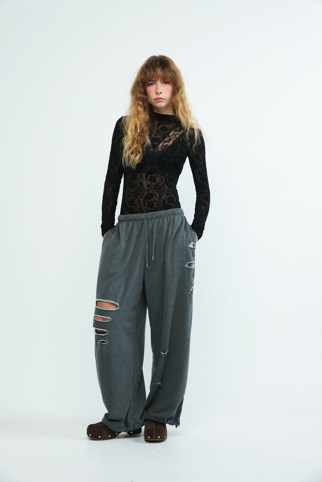 Dark grey loose-fitting joggers with distressed ripped details and drawstring waistband shown from the front