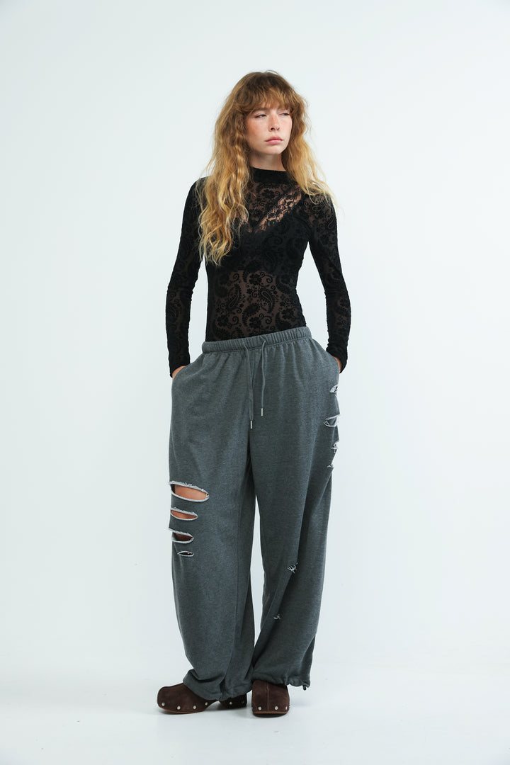Grey distressed wide-leg joggers with drawstring waist and ripped knee details shown from the front