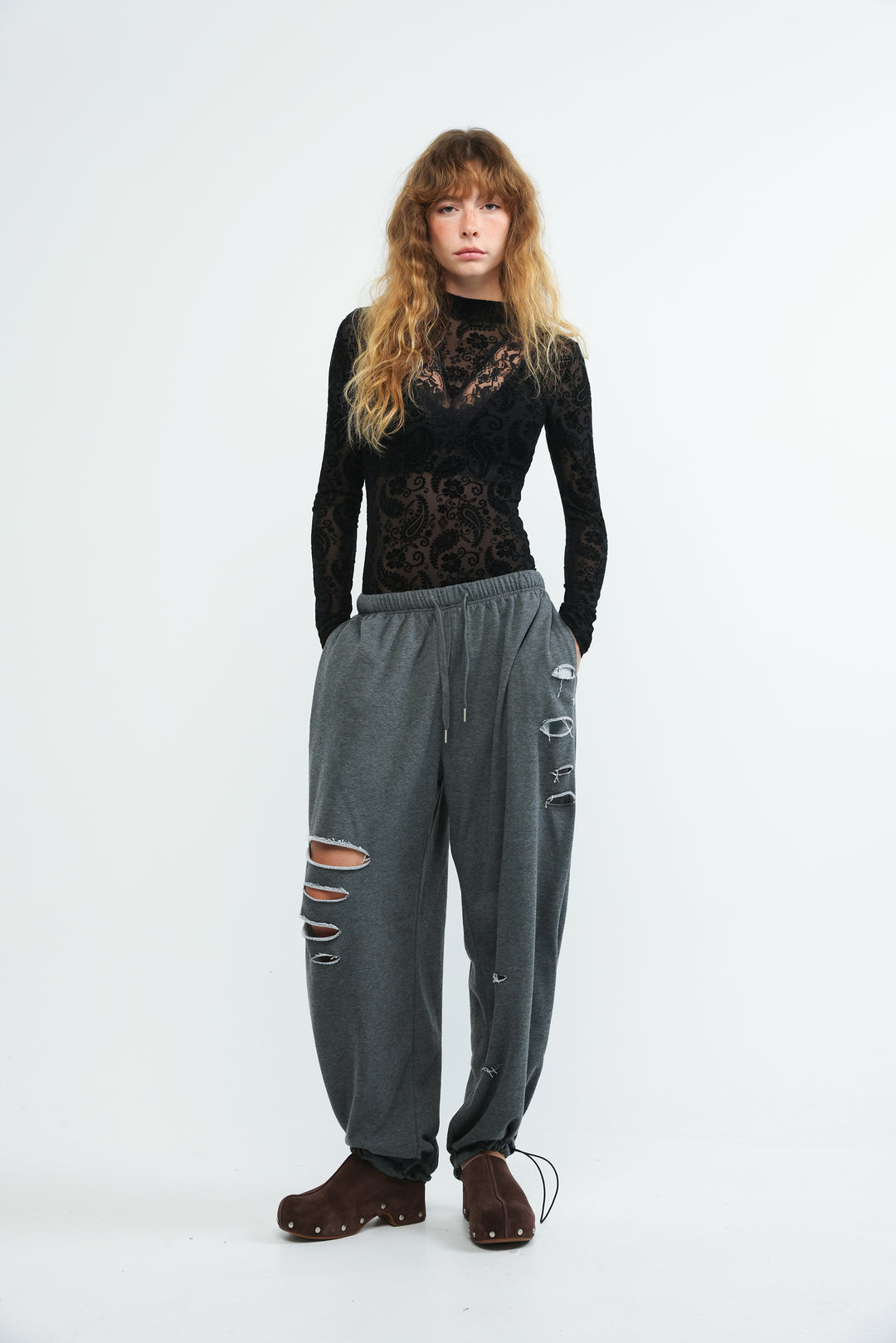 Dark grey scissors joggers with elastic waistband drawstring and distressed holes at the knees shown from the front