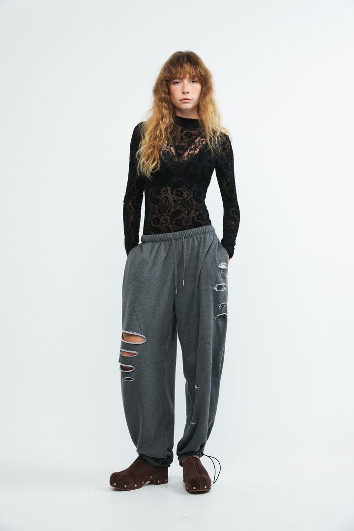 Dark grey scissors joggers with elastic waistband drawstring and distressed holes at the knees shown from the front