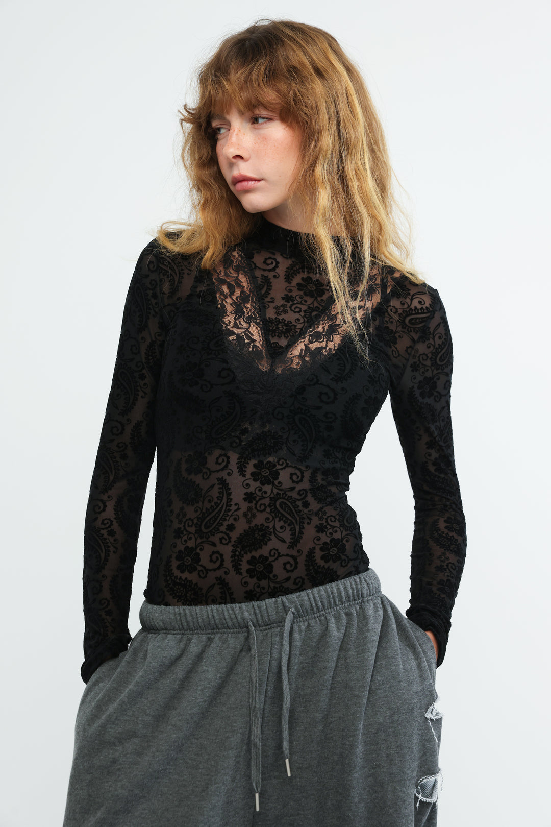 Claim black bodysuit featuring a long-sleeved top with intricate floral and paisley lace patterns in front view