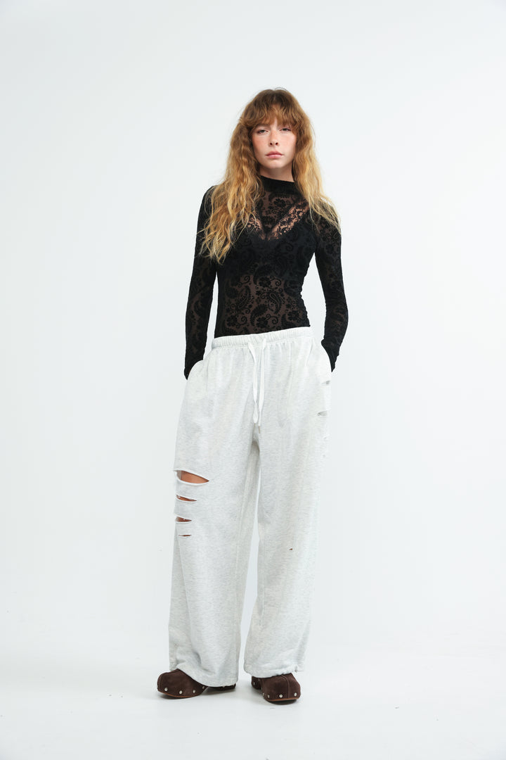 White wide-leg pants with rips and drawstring waistband shown from the front titled scissors grey joggers