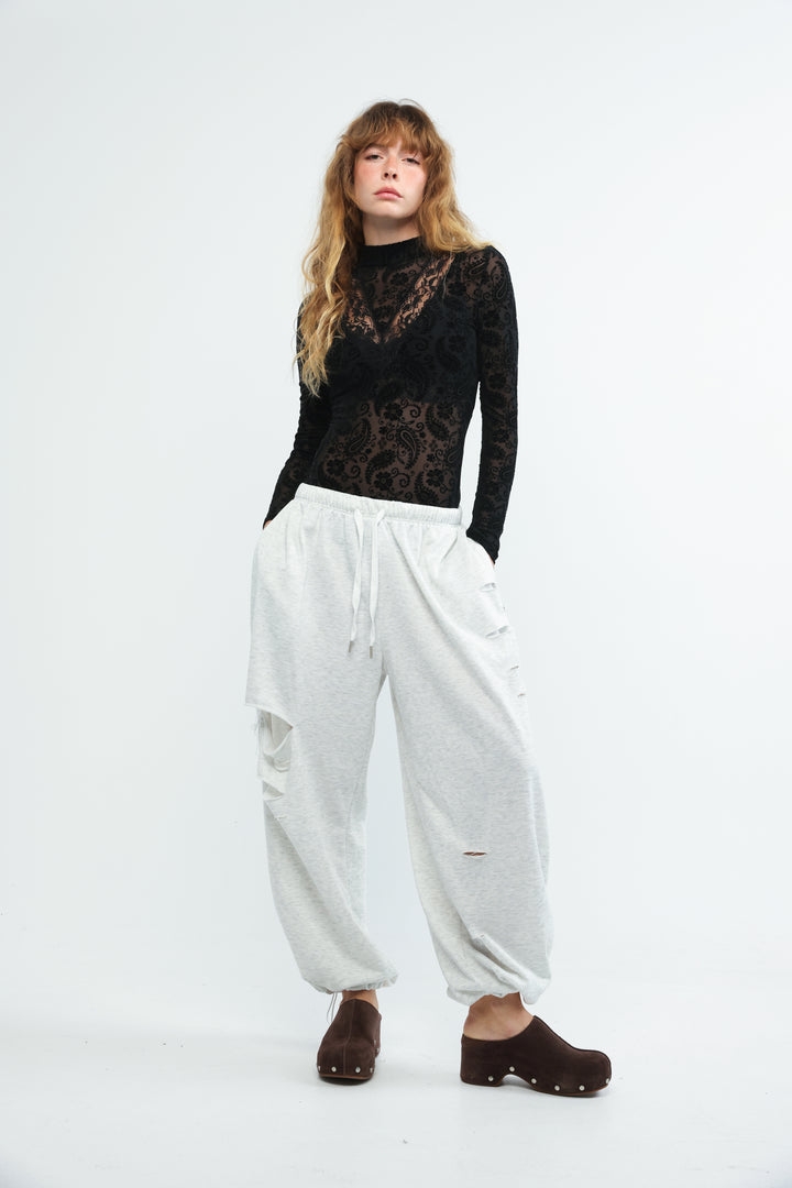Black bodysuit paired with white cargo pants featuring distressed details and a drawstring waist viewed from the front