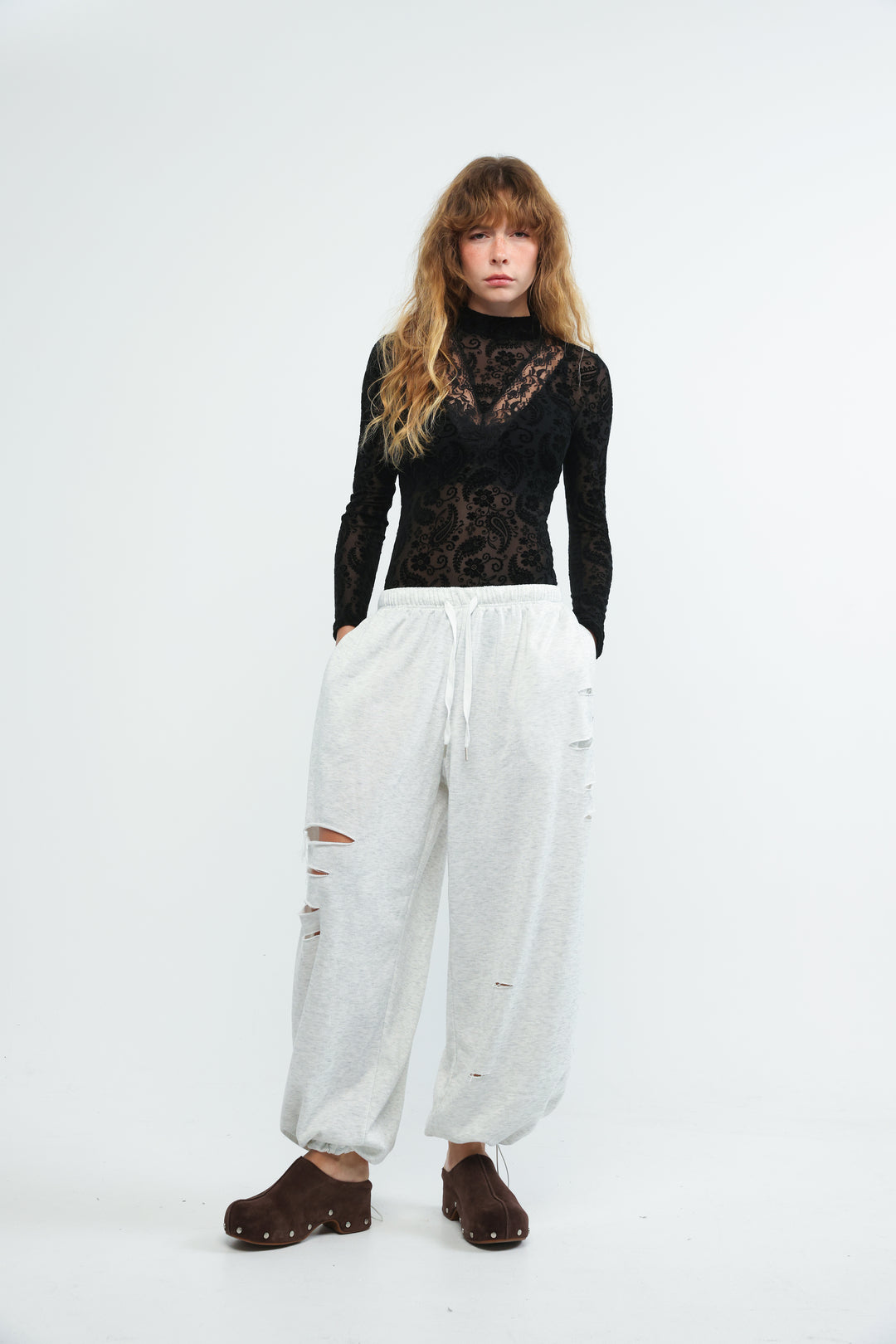 Black lace long-sleeve top with intricate floral patterns paired with grey joggers shown from the front