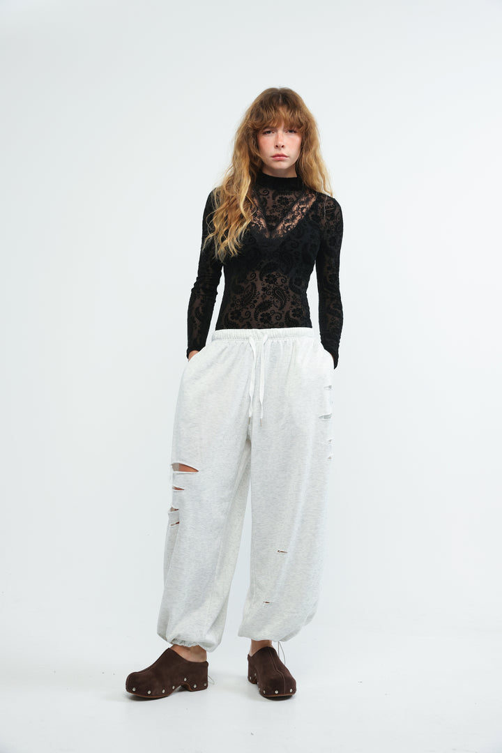 Black lace long-sleeve top with intricate floral patterns paired with grey joggers shown from the front
