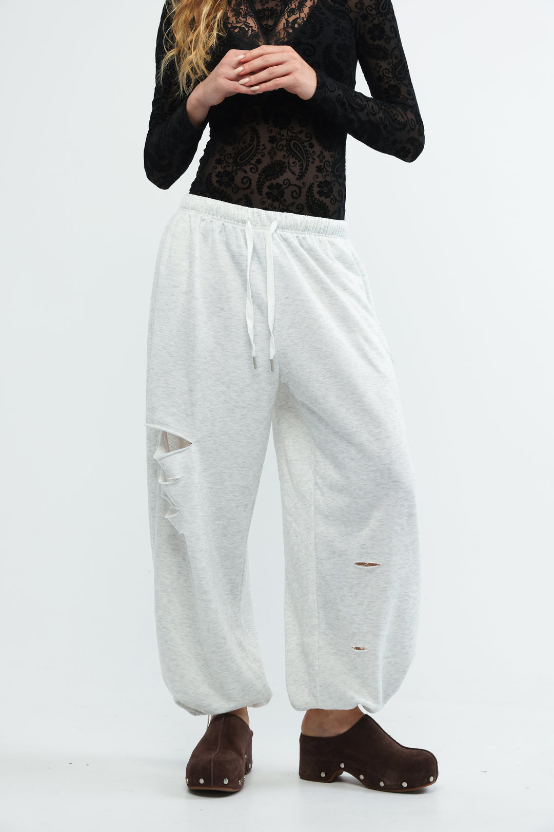 White scissors grey joggers with loose fit, elastic waistband, and distressed ripped details shown from the front