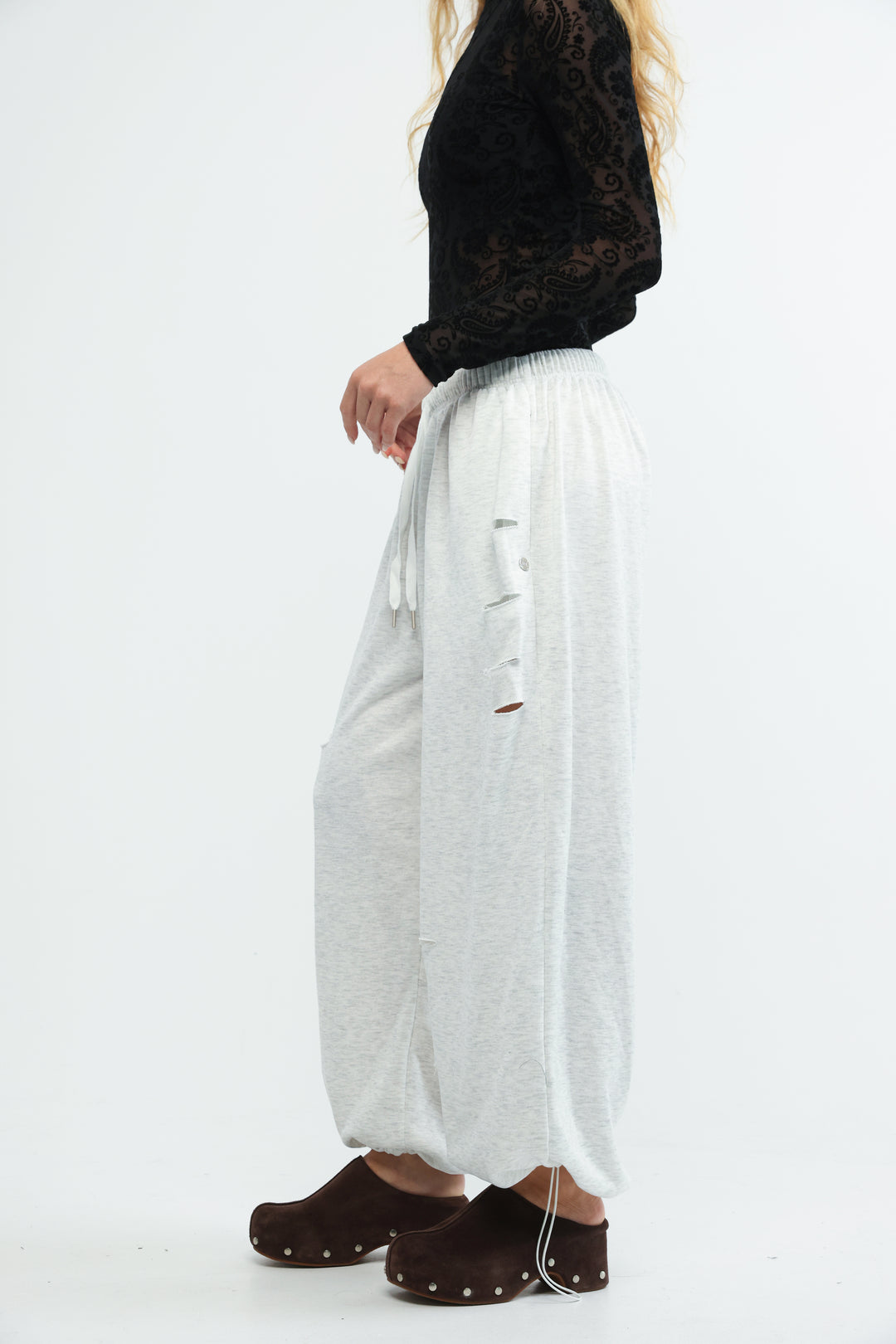 Grey joggers with a drawstring waist and distressed side slits shown from the front