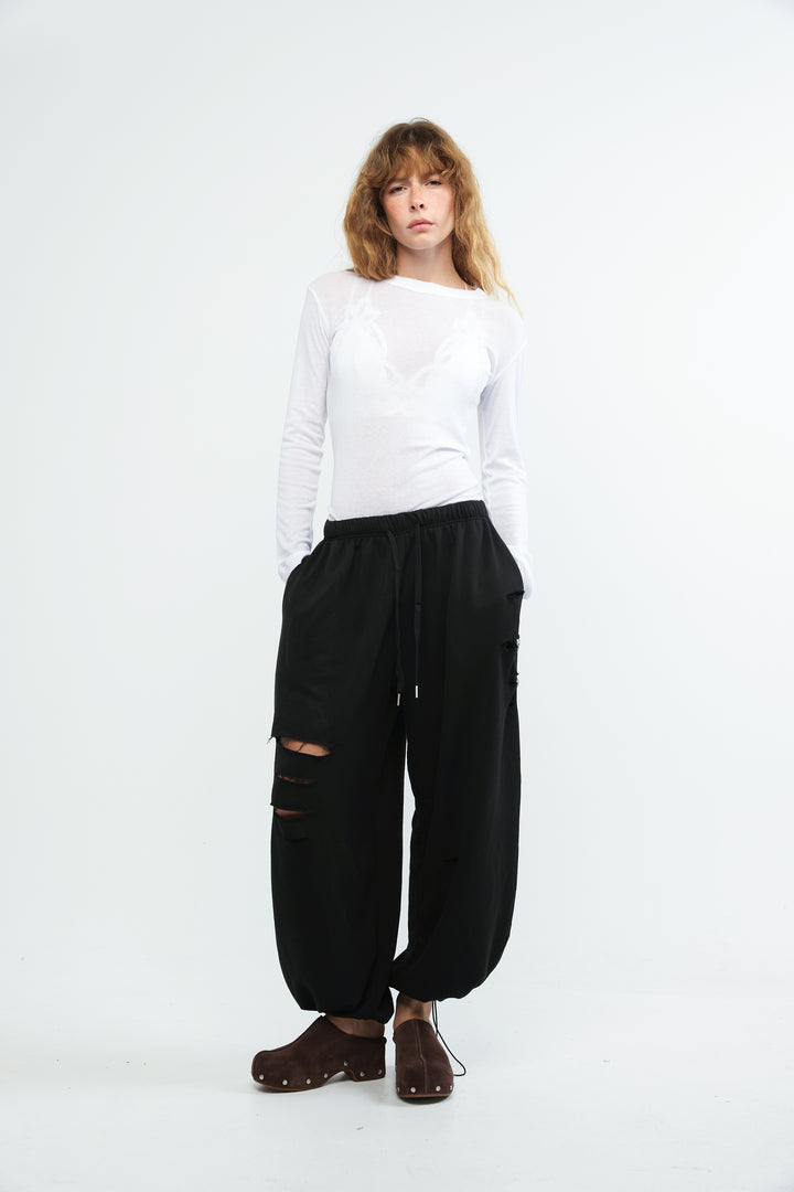 Black wide-leg joggers with distressed ripped details and drawstring waistband shown from the front
