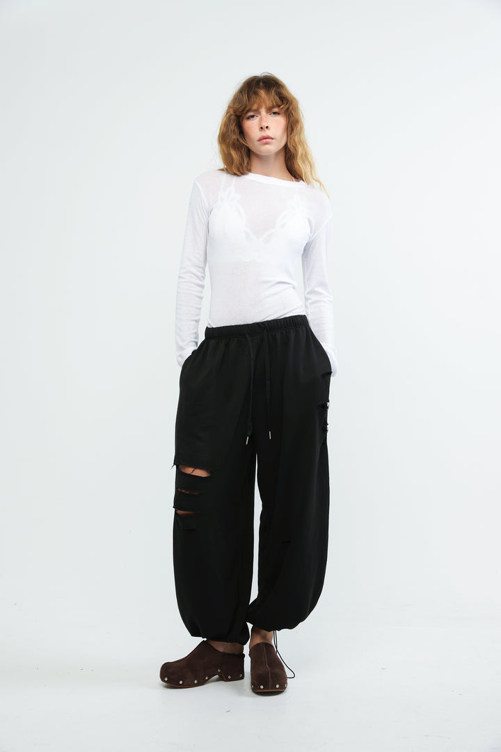 Black joggers with loose fit ripped knee details and drawstring waistband shown from front view