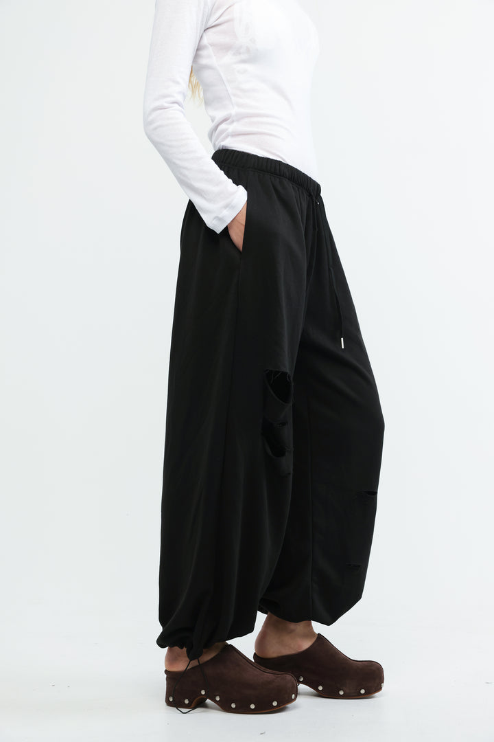 Black wide-leg joggers with relaxed flowing silhouette and subtle distressing details shown from the front