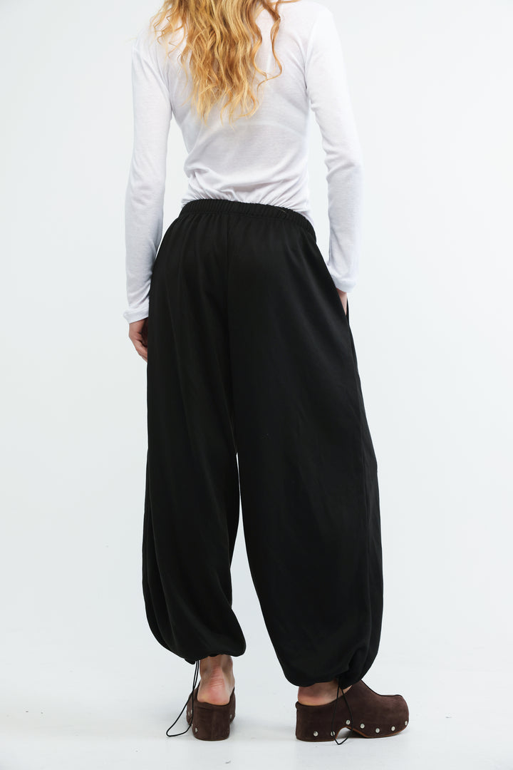Black scissors joggers with loose fit elastic waist and flowing balloon silhouette shown from front view