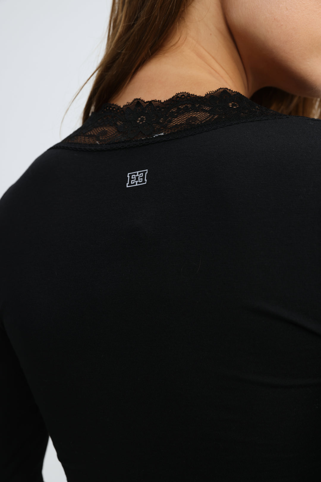 Mysterious black shirt long-sleeved top with delicate black lace trim at neckline and small white logo on back