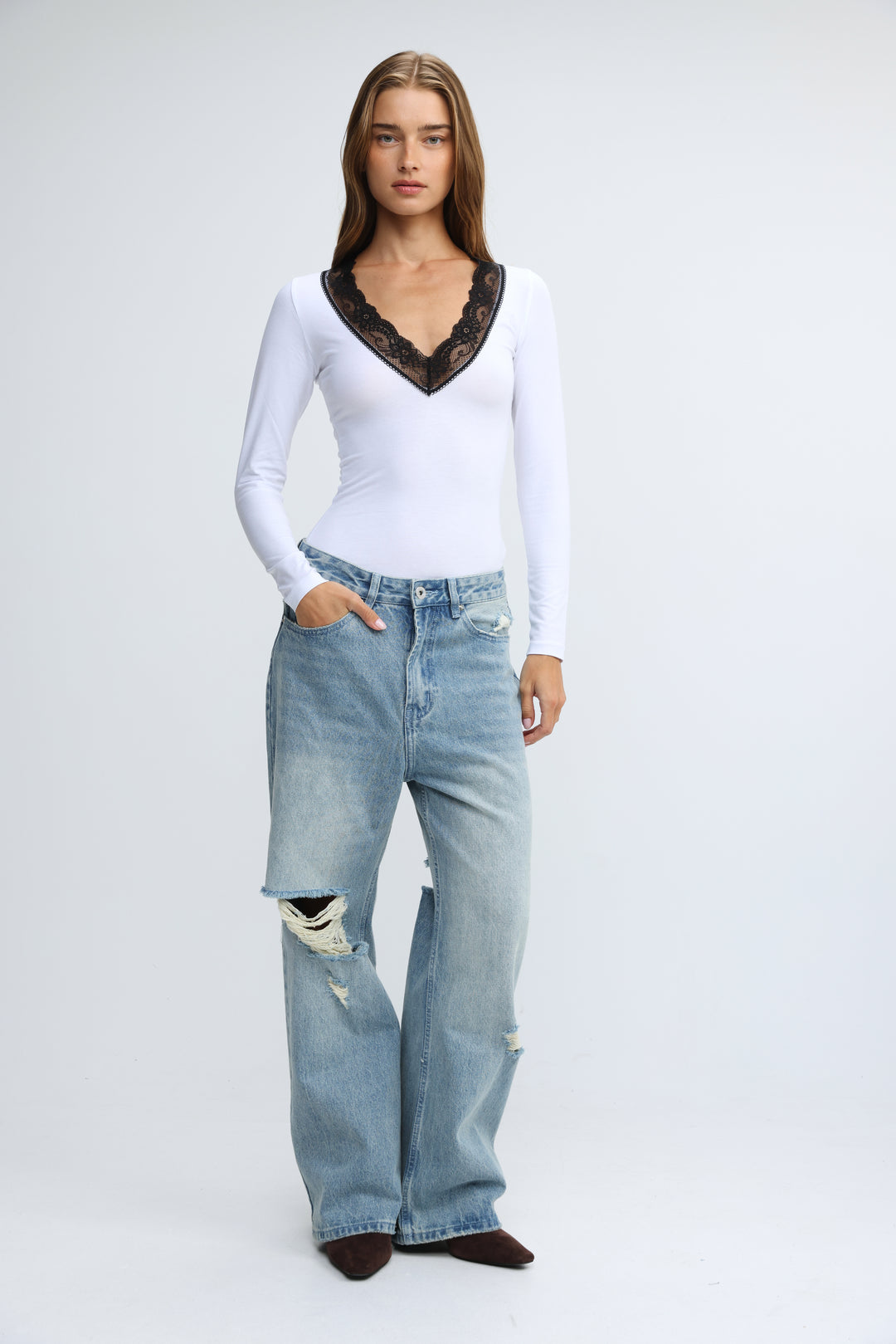 Mysterious white long-sleeved top with black lace trim at the neckline shown from the front