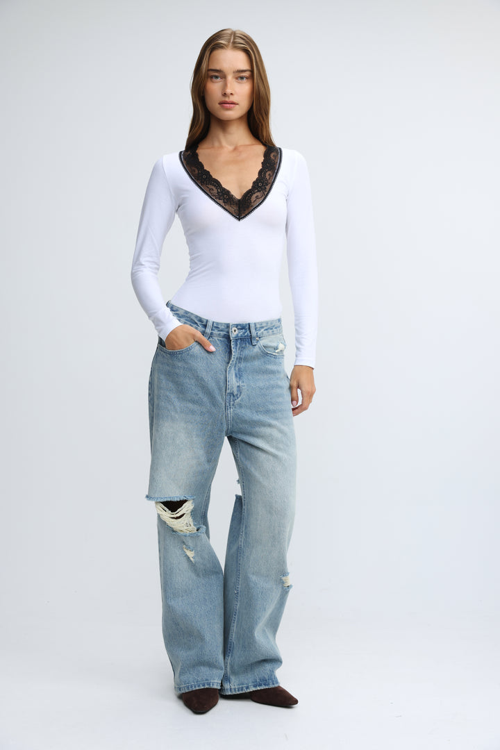 Mysterious white long-sleeved top with black lace trim at the neckline shown from the front