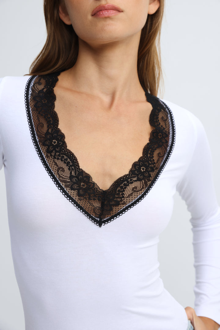 White long-sleeved shirt with black floral lace trim around v-neckline, front view, called mysterious white shirt