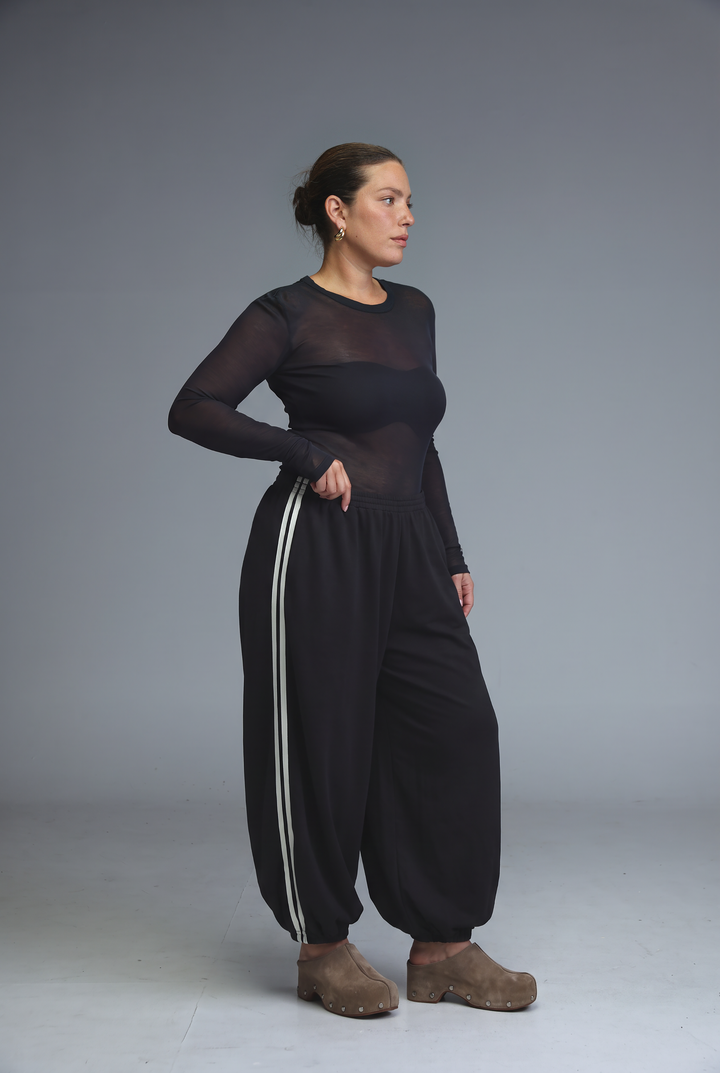 Black sheer long-sleeved top with solid black bodice and side stripes paired with ballooning leopard striped joggers front view