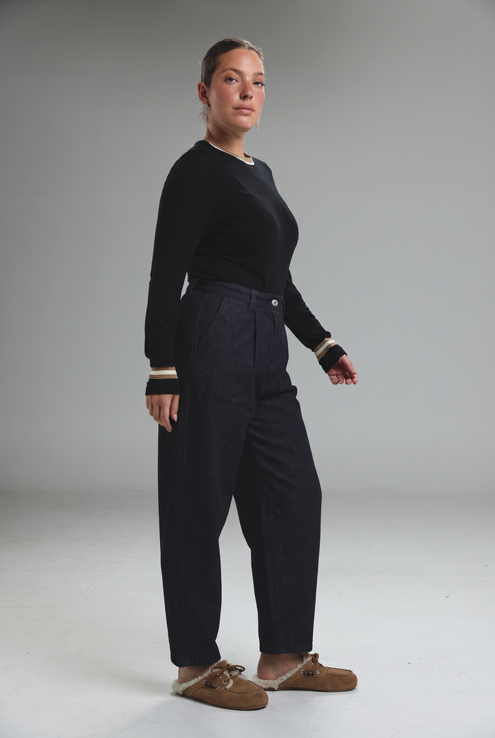 Black long-sleeved sweater with ribbed cuffs and v-neckline shown from the front with light blue tailored denim