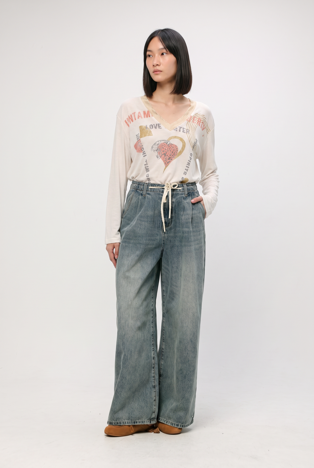 Star 461 blue denim high-waisted wide-leg jeans paired with a cream long-sleeved graphic tee featuring a heart and text design