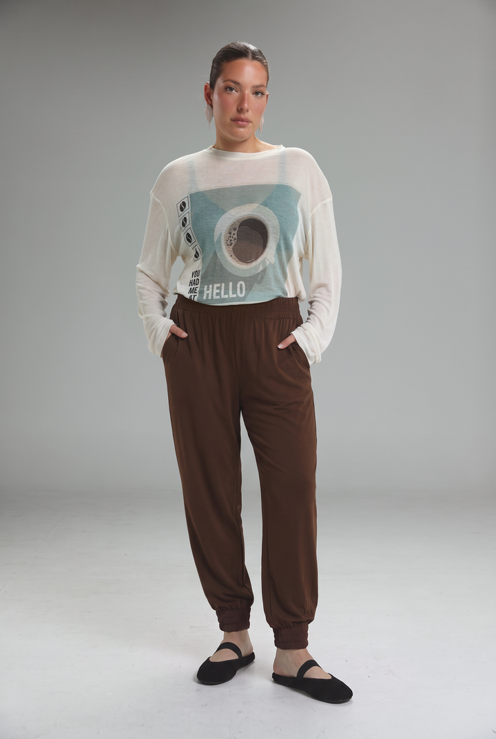A woman wearing bestie navy joggers shown front view paired with a white sweatshirt featuring a light blue and black eye graphic