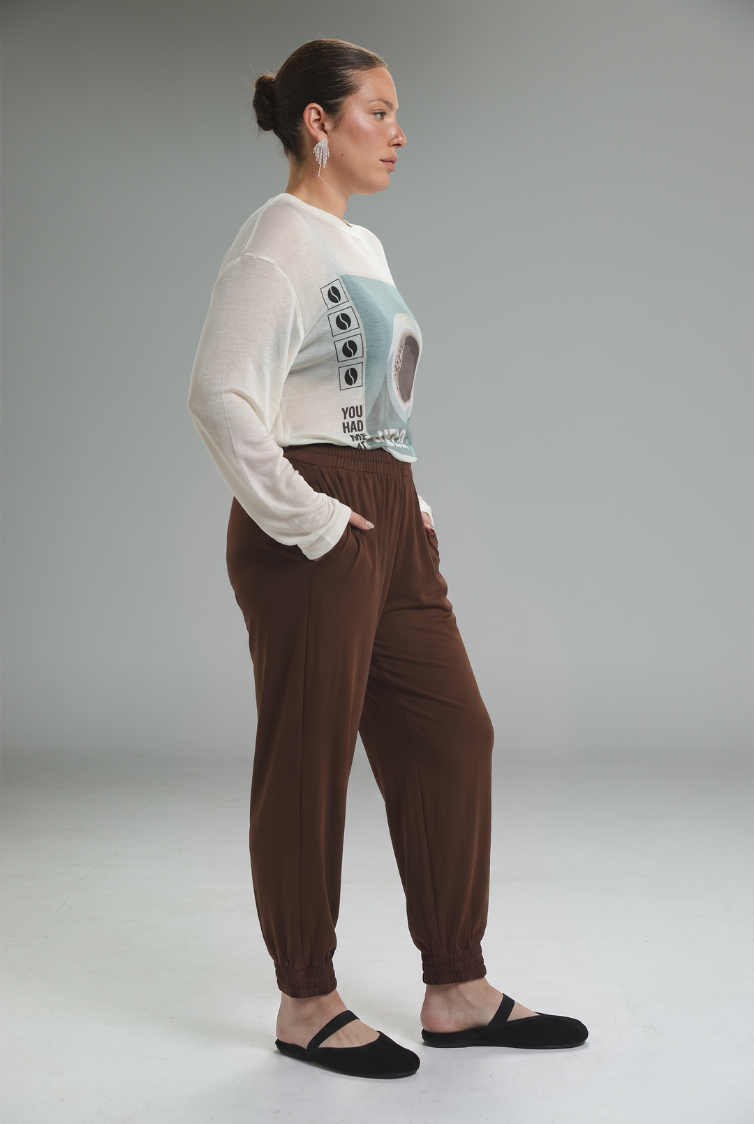 A front view of bestie navy joggers with brown elastic waist worn with a white long-sleeved graphic top