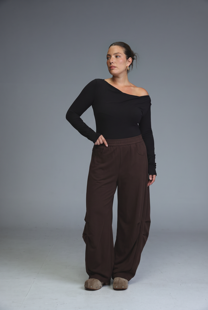 The model wears 646 black joggers shown front view paired with a black one-shoulder long-sleeved top and brown trousers