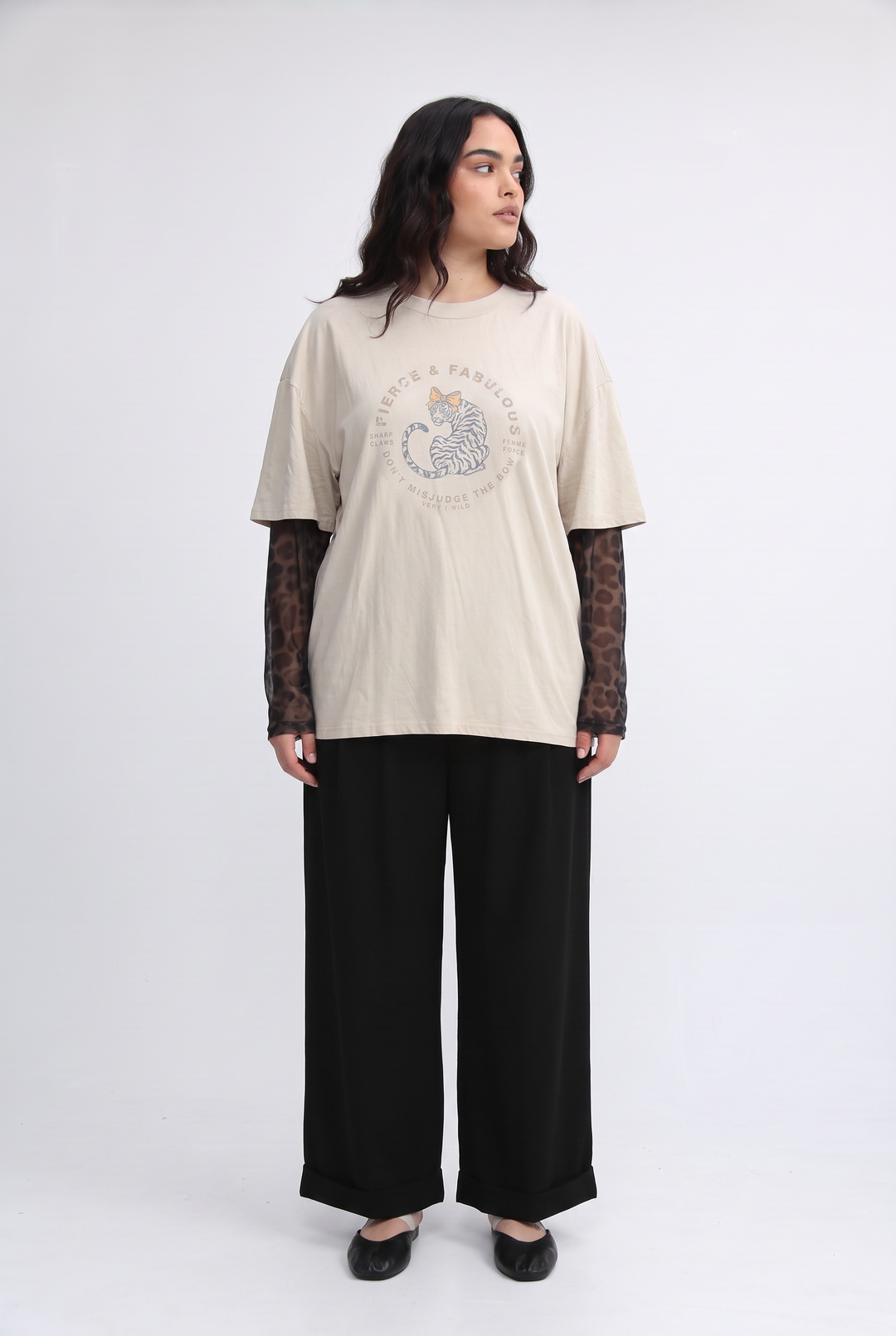 Beige oversized t-shirt with circular tiger graphic and text worn over sheer leopard mesh long-sleeve top front view