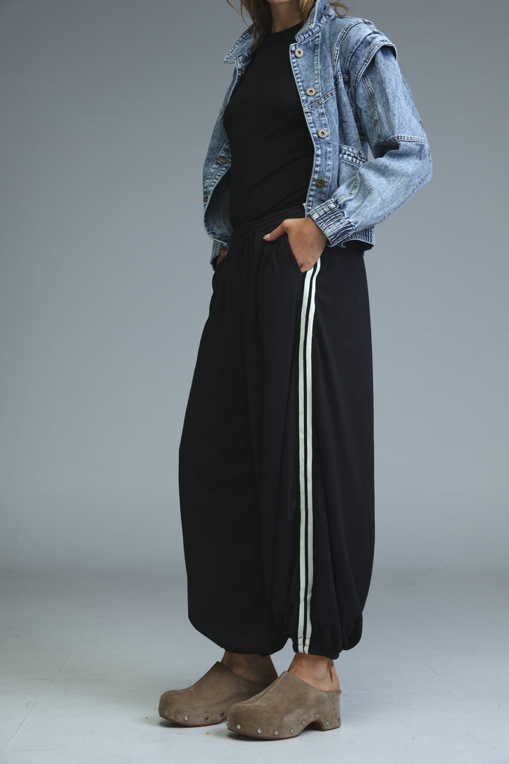 Black wide-leg ballooning joggers with two vertical white stripes down the side shown from the front