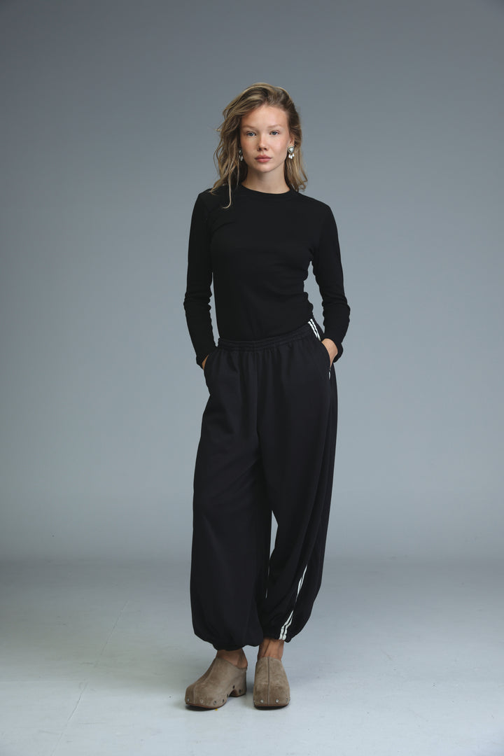 Black long-sleeved top with round neckline and subtle white stripes along side seams paired with ballooning black striped joggers