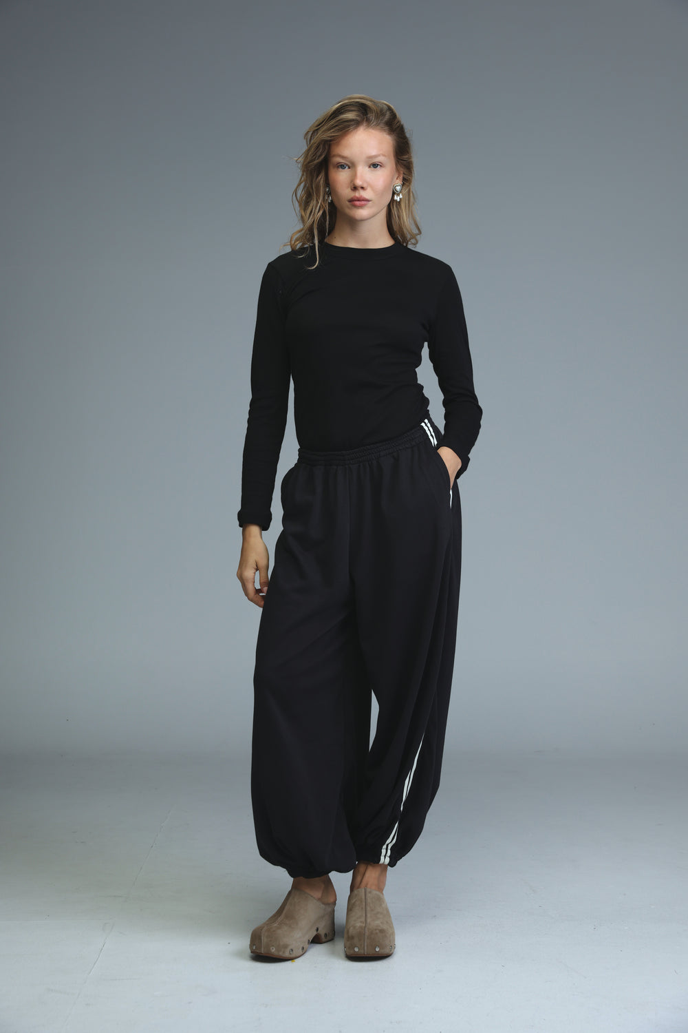 Black long-sleeved top with round neckline and subtle white stripes along side seams shown from the front