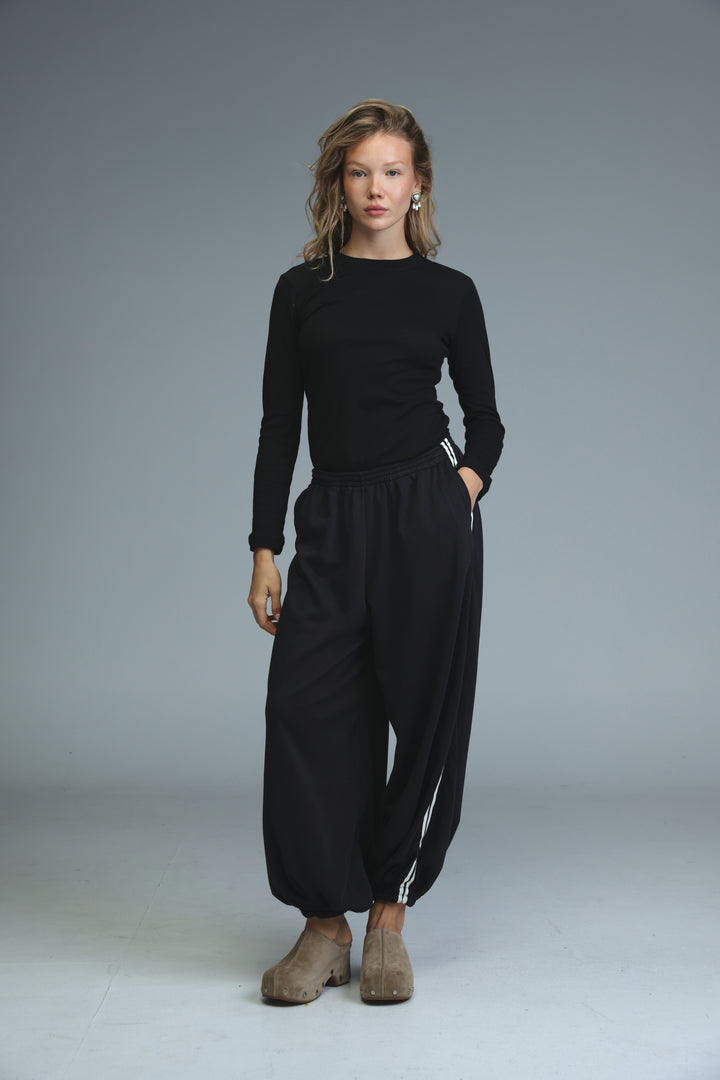 Black long-sleeved top with round neckline and subtle white stripes along side seams shown from the front