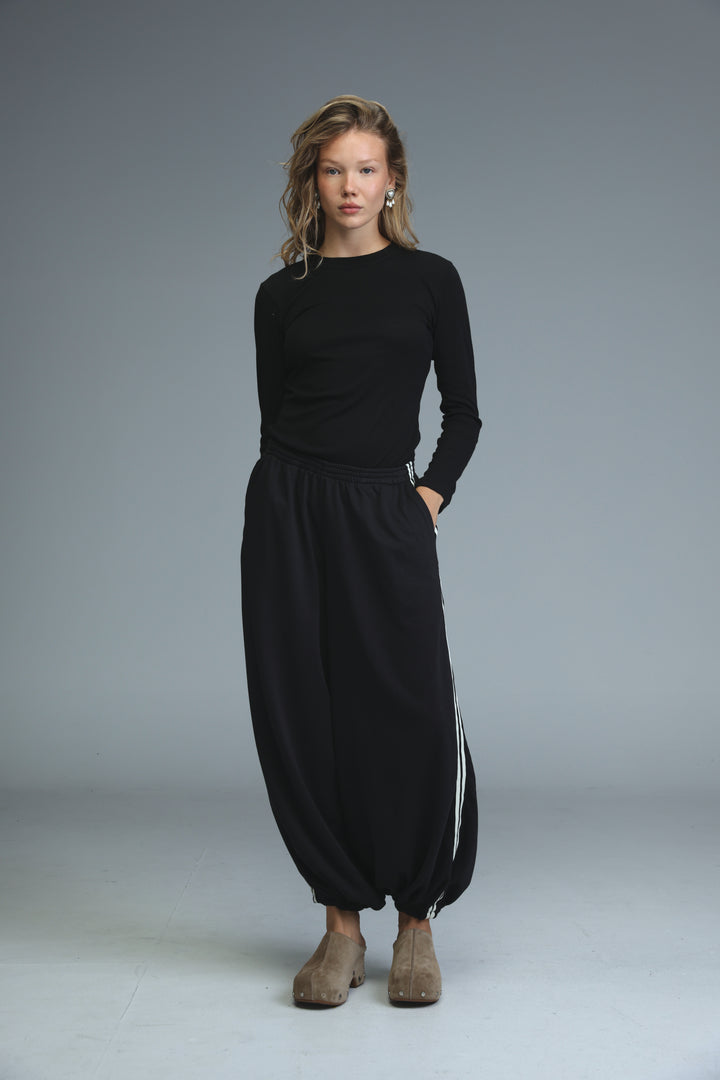 Ballooning black striped joggers paired with a black long-sleeved top with round neckline and side seam detailing