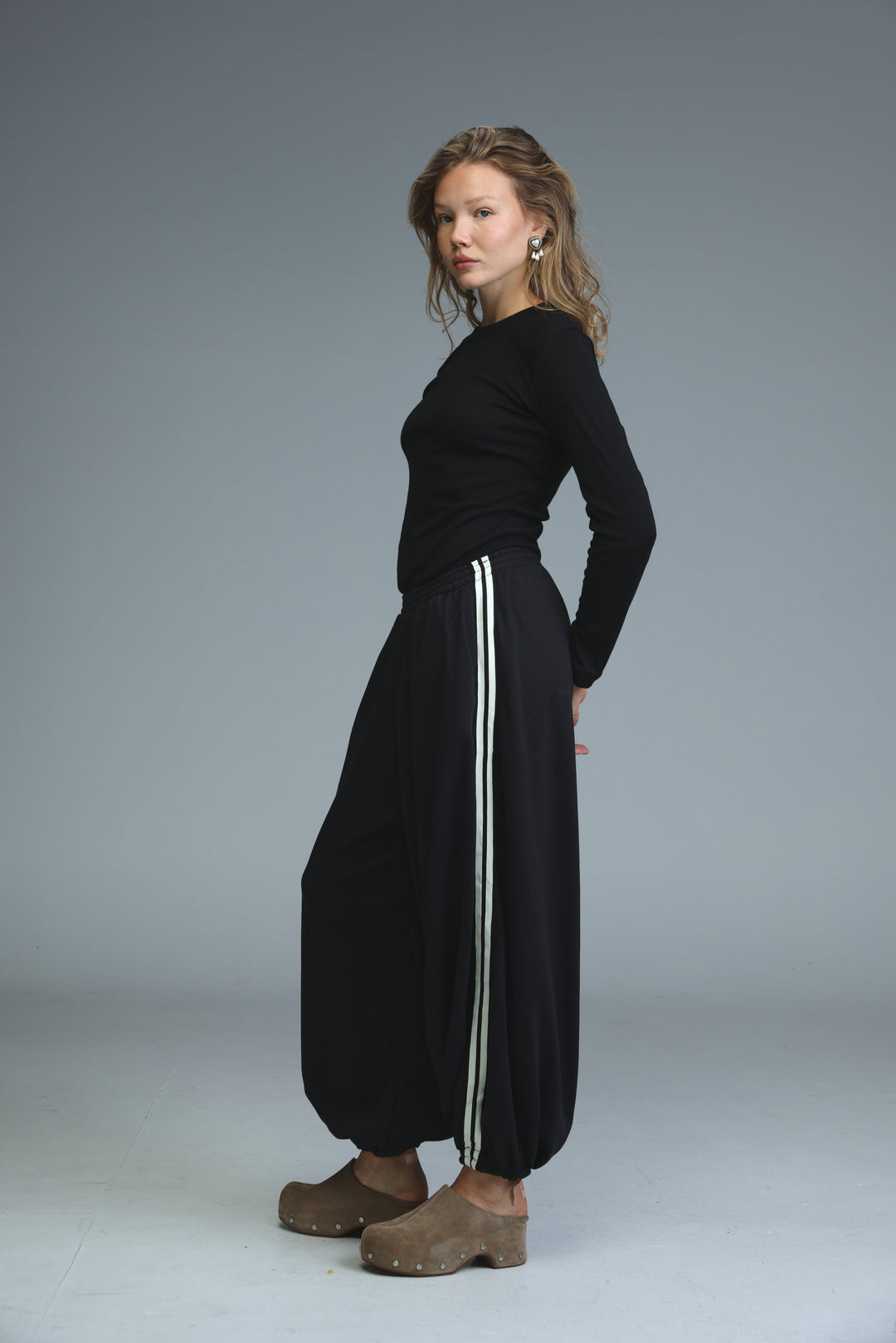 Ballooning black striped joggers with wide legs and two vertical white stripes down the sides shown from the front