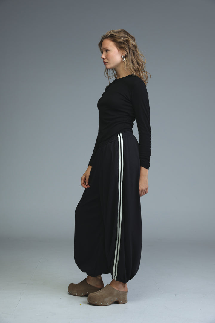 Black long-sleeved top with relaxed fit and subtle ribbed texture paired with ballooning black striped joggers front view