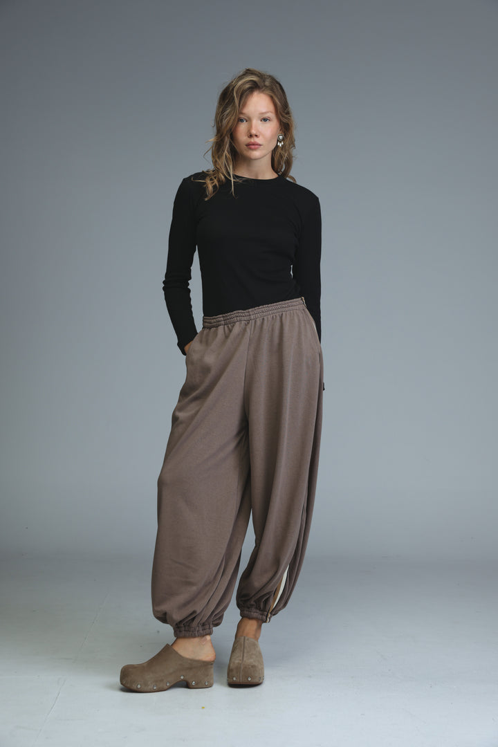 Brown loose-fitting harem pants with elastic cuffs and relaxed silhouette shown from the front