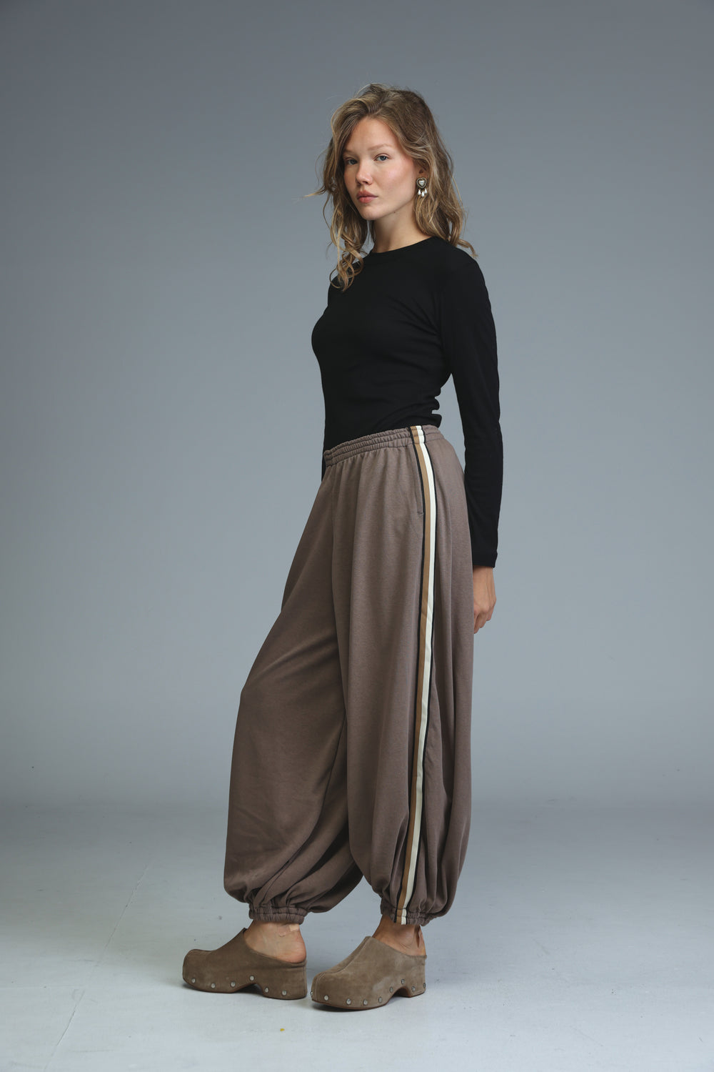 Ballooning brown striped joggers with a vertical stripe down the side shown from the front view