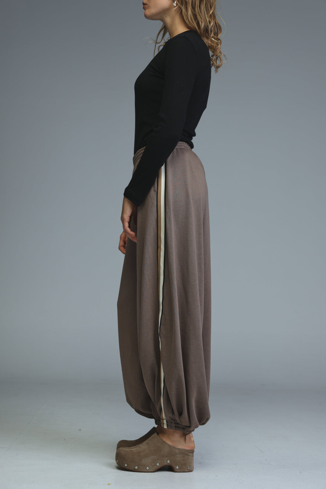 Ballooning brown striped joggers with loose wide legs and a side cream stripe shown from the side view