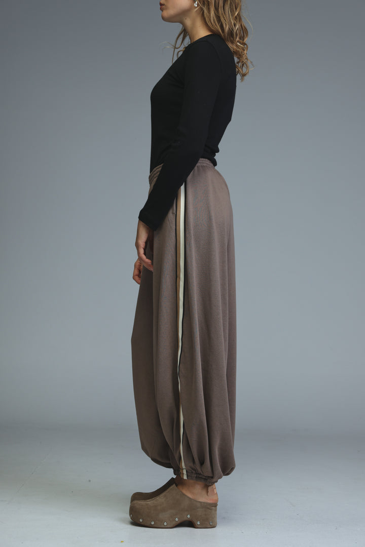Ballooning brown striped joggers with loose wide legs and a side cream stripe shown from the side view