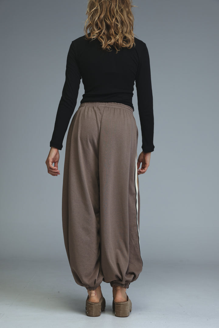 Brown ballooning joggers with a white vertical stripe down the side shown from the front view