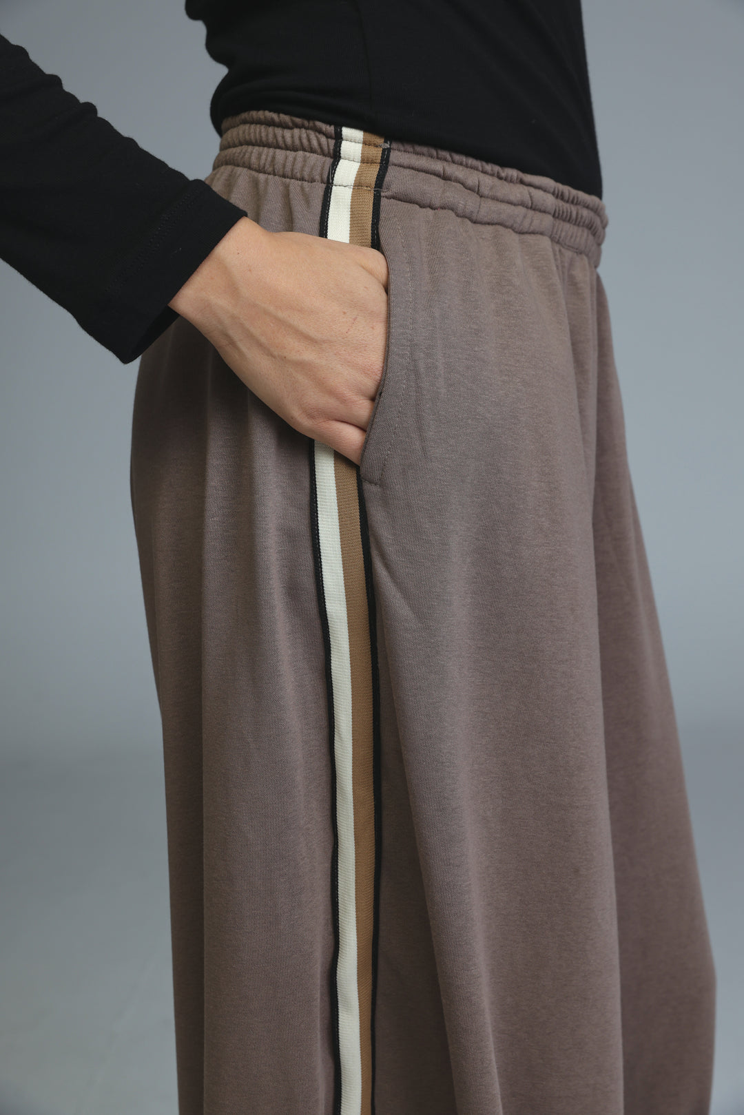 Brown wide-leg sweatpants with a vertical stripe detail down the side shown from the front view