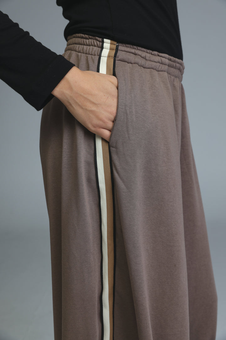 Brown wide-leg sweatpants with a vertical stripe detail down the side shown from the front view