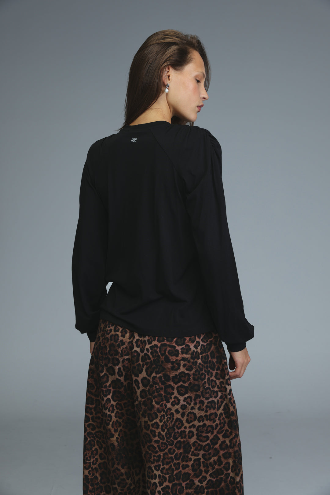 Black long-sleeved padded shirt with a subtle logo on the back neckline shown from the back view